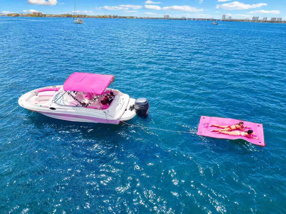 Guest relaxing on the floating mat beside the 26ft pink Sea Ray Miami