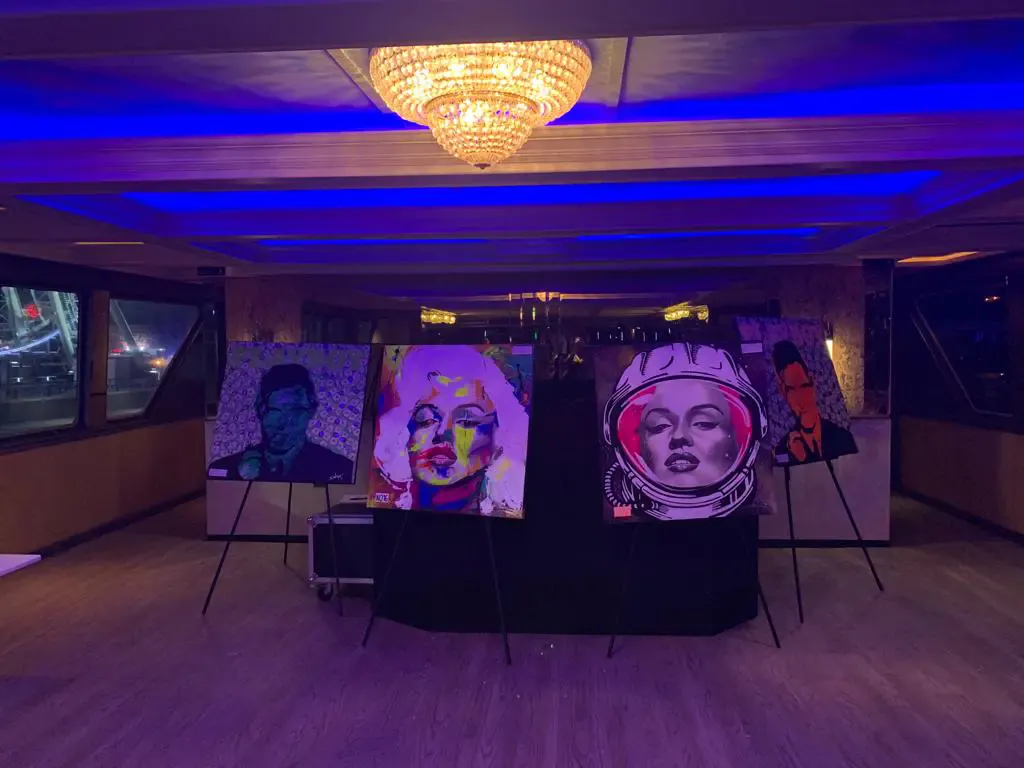 Pop-art paintings displayed on easels at an Art Basel gallery event on a yacht in Miami