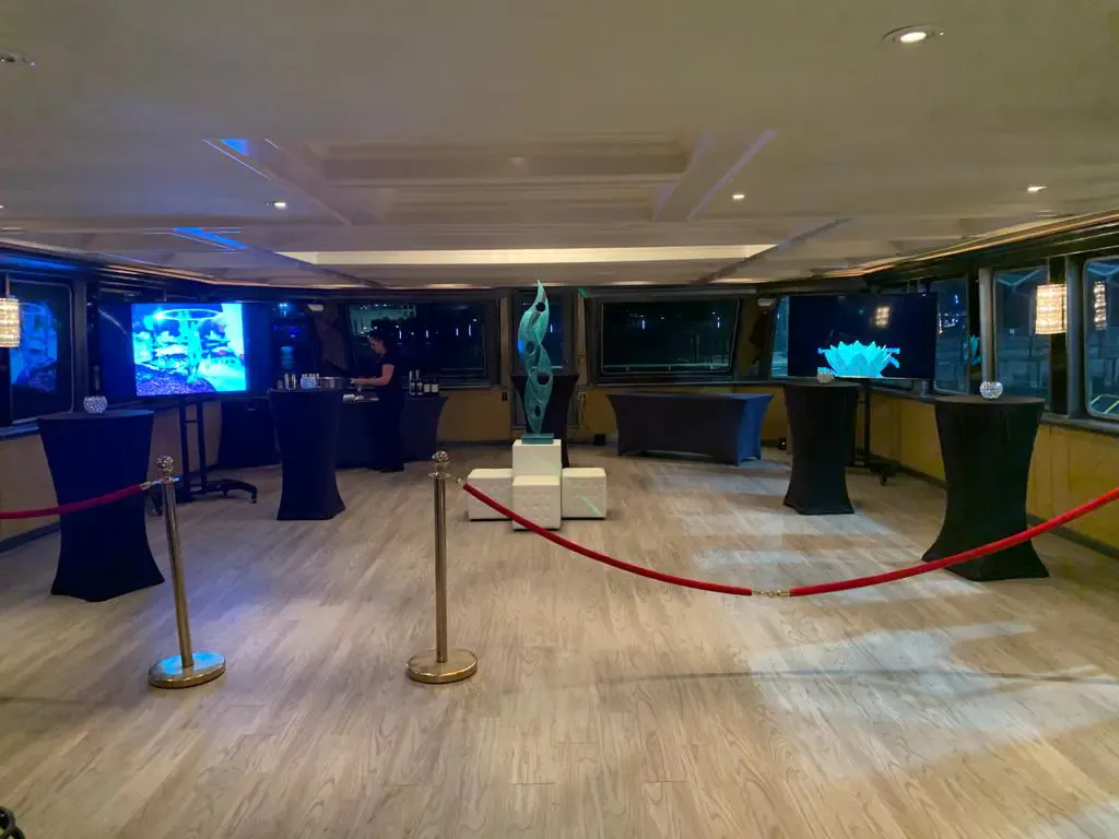 Sculpture displayed behind velvet ropes at an Art Basel private event on a yacht