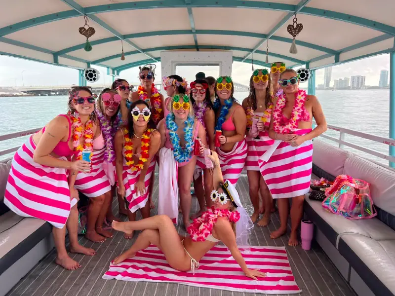 Bachelorette party bride squad in pink leis and captain hat celebrating on a Miami boat rental