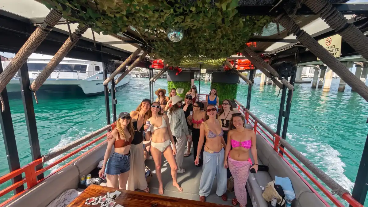 Party cruise guests enjoying music and drinks under canopy on Cat Lux 50ft party boat Miami