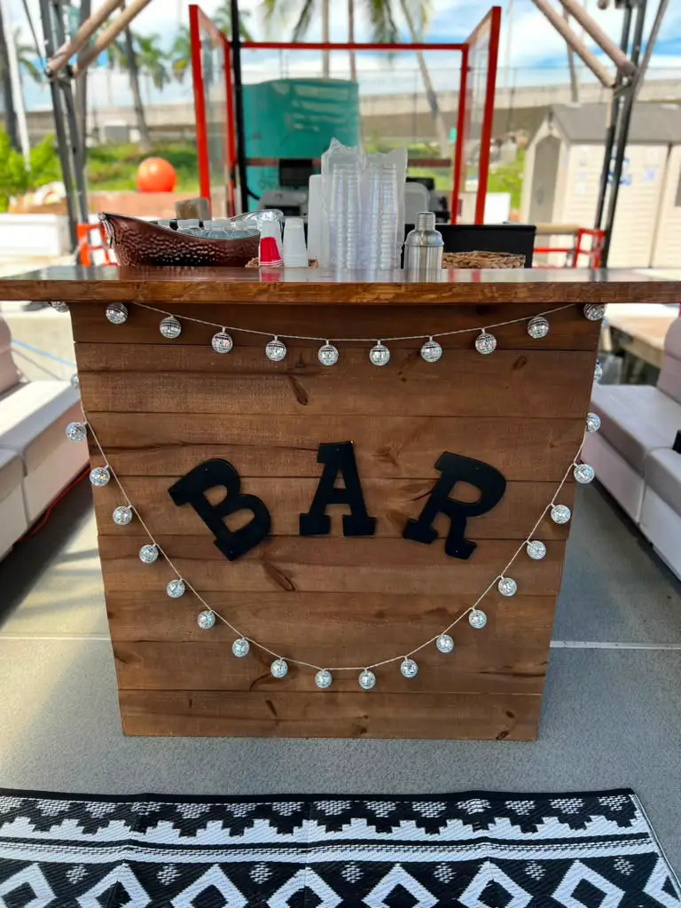 Dedicated onboard wooden bar with disco lights and cocktail setup on Cat Lux party boat Miami