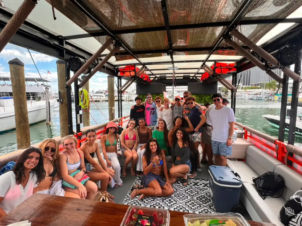 Large private group enjoying catering and drinks on Cat Lux party cruiser deck at Miami Beach Marina