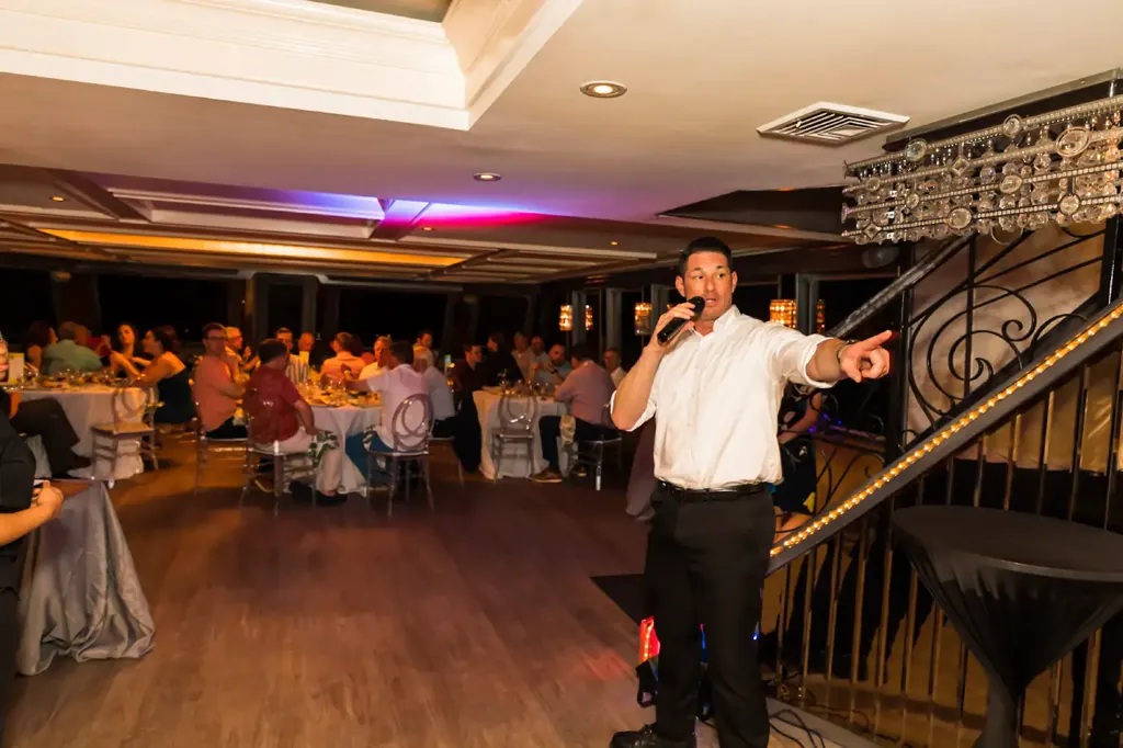 Host speaking to seated guests at a corporate yacht event in Miami in December
