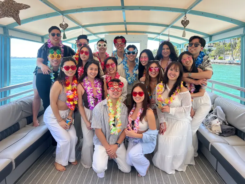 Guests with tropical leis and heart sunglasses on 35ft Moana Flow birthday party boat rental Miami