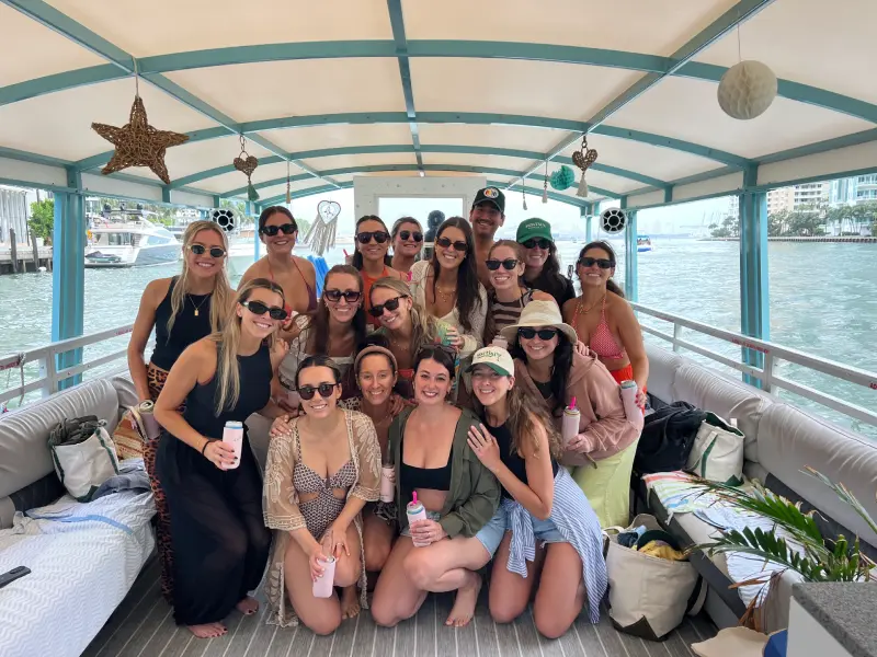 Large group of guests posing inside spacious covered deck on 35ft Moana Flow Boat Miami charter