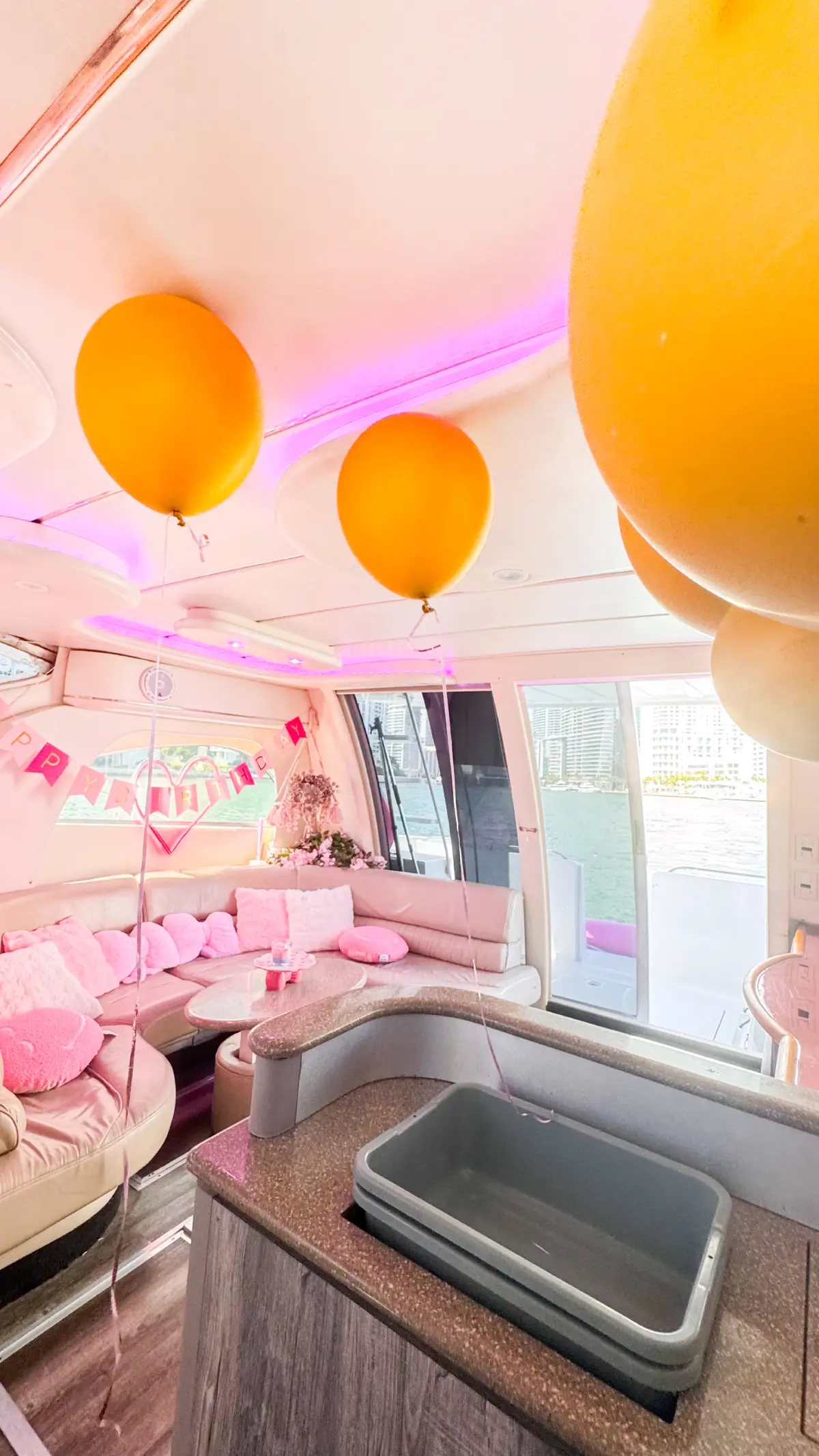 Pink yacht rental Miami interior with gold balloons and pink lounge seating