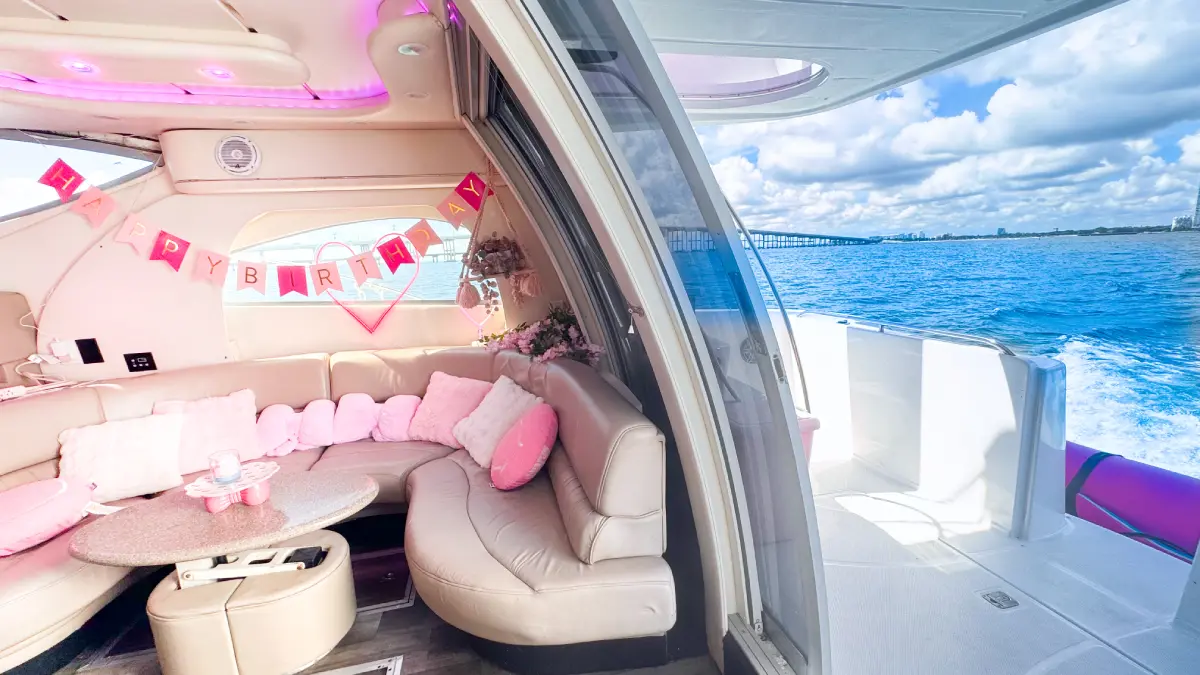 Pink yacht Miami salon with birthday banner and view of Biscayne Bay